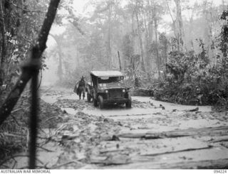 SOUTH BOUGAINVILLE, 1945-07-20. A JEEP AND TRAILER OF 2/11 FIELD REGIMENT, CARRYING SUPPLIES TO 22 FIELD BATTERY SITE WEST OF THE MOBIAI RIVER ALONG THE BUIN ROAD. THE PICTURE SHOWS HEAVY RAIN AND ..