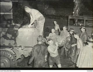 KIRIWINA, TROBRIAND ISLANDS, PAPUA. C. 1943-12. IN TORRENTIAL RAIN RAAF AIRMEN UNLOADING A TRUCK LOADED WITH CHRISTMAS MAIL FOR THE POST OFFICE