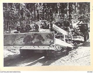 BOUGAINVILLE. 1945-05-25. TROOPS OF 2 FIELD REGIMENT, ROYAL AUSTRALIAN ARTILLERY, USE A BULLDOZER TO TOW A 25-POUNDER ALONG THE CORDUROY SECTION OF THE BUIN ROAD TO PROVIDE ARTILLERY SUPPORT FOR ..