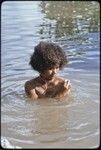 Young woman, wearing shell necklaces, bathes in shallow water