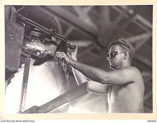 LAE, NEW GUINEA. 1944-12-21. SAPPER A L HANNAHAN, 2/3 FORESTRY COY, SHARPENING AND SETTING A CIRCULAR SAW AT THE BUSU MILL