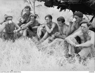 RAMU VALLEY, NEW GUINEA, 1943-10-20. MEMBERS OF THE 2/7TH AUSTRALIAN INDEPENDENT COMPANY EATING LUNCH FROM THEIR FIELD OPERATIONS RATION. LEFT TO RIGHT:- SX17170 TROOPER A.J. PETERS; NX136620 ..