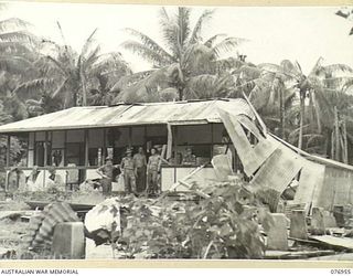 JACQUINOT BAY, NEW BRITAIN. 1944-11-12. MEMBERS OF THE MORTAR PLATOON, 14/32ND INFANTRY BATTALION ATTACHED TO B COMPANY, 1ST NEW GUINEA INFANTRY BATTALION, ON THE VERANDAH OF THE WRECKAGE OF OSCAR ..