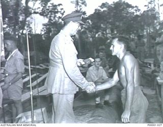 THE SOLOMON ISLANDS, 1945-01-12. A WINNER RECEIVES CONGRATULATIONS AND HIS PRIZE AT A COMBINED ANZAC SPORTS MEETING AT BOUGAINVILLE ISLAND. (RNZAF OFFICIAL PHOTOGRAPH.)