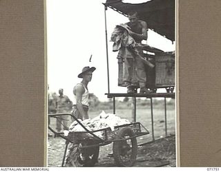 LAE, NEW GUINEA, 1944-03-25. N271221 PRIVATE R. S. WATSON (LEFT), AND N206061 PRIVATE V. E. WIGGINS, MEMBERS OF THE 1ST MOBILE HOSPITAL LAUNDRY UNIT PLACE WASHED AND DRIED CLOTHES INTO A HAND TRUCK ..