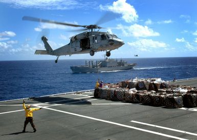 US Navy (USN) Aviation Boatswain's Mate Handler Second Class (AB2) Brandon Reyes (bottom left) signals the pilot of an MH-60 Knighthawk helicopter from Guam based USN Helicopter Sea Combat Squadron 25 (HSC-25) during Vertical Replenishment (VERTREP) operations on the flight deck of the USN Military Sealift Command (MSC) Mercy Class Hospital Ship USNS MERCY (T-AH 19) during their five-month deployment in the Pacific Region. The MERCY will participate in humanitarian assistance and civic action programs with civilian organizations at several islands in the Pacific Region. The MERCY is capable of supporting medical and humanitarian assistance needs. It is configured with special medical...