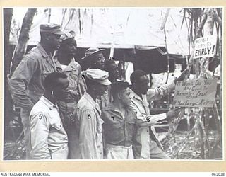 DREGER HARBOUR, NEW GUINEA. 1943-12-06. MEMBERS OF THE 870TH UNITED STATES AVIATION ENGINEER BATTALION READING A SIGN OUTSIDE THE MEDICAL DISPENSARY WHICH SAYS: "IT WONT DO YOU ANY GOOD TO REMEMBER ..