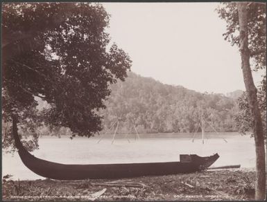 A canoe on the shore of Pirihadi Bay with native fishing station in background, Ysabel, Solomon Islands, 1906 / J.W. Beattie