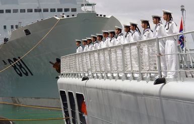 Chinese Peoples Liberation Army Navy Sailors from the Luhu Class (Type 052) Guided Missile Destroyer QINGDAO (DDG 113) man the rails as their ship arrives at Naval Station Pearl Harbor, Hawaii, for a Goodwill Visit on Sept. 6, 2006. The visit provides an excellent opportunity to enhance cooperation between the two navies and underscores the United States commitment to supporting ongoing cooperative efforts in the Pacific Region. In the background is the PLA Navy Fuquing Class Replenishment Ship HONGZEHU (AOR 881). (U.S. Navy photo by CHIEF Mass Communication SPECIALIST Joe Kane) (Released)