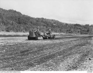 FINSCHHAFEN, NEW GUINEA, 1943-10-28. TROOPS OF THE 2/1ST AUSTRALIAN MECHANICAL EQUIPMENT COMPANY WORKING ON THE AIRSTRIP. THEY ARE:- NX82496 SAPPER G.A. THOMSON (LEFT, AT CONTROLS OF TRACTOR); ..