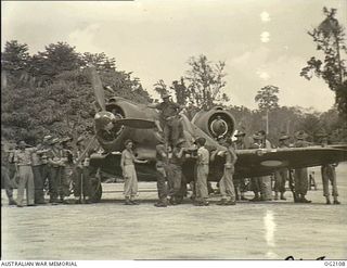 TOROKINA, BOUGAINVILLE ISLAND, SOLOMON ISLANDS. 1945-01-19. RAAF AND AIF PERSONNEL COMPARE NOTES AS THE LATTER ARE INITIATED INTO THE MYSTERIES OF THE AUSTRALIAN BUILT BOOMERANG AIRCRAFT OF NO. 5 ..