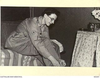 LAE AREA, NEW GUINEA. 1944-11-06. PRIVATE F.E. TATE, AUSTRALIAN ARMY MEDICAL WOMEN'S SERVICE, AT 2/7 GENERAL HOSPITAL LACING HER JUNGLE BOOTS. REMARKABLE INGENUITY IN THE IMPROVISATION OF SLEEPING ..