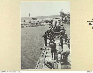 BOUGAINVILLE ISLAND, 1945-01-19. SAPPERS OF THE 5TH FIELD COMPANY, LAYING DECKING ON THE STRINGERS OF A NEW BRIDGE WHICH THEY ARE BUILDING ACROSS THE REINI RIVER