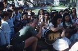 Native women and children sitting in a group with guitars, Likiep Atoll, August 20, 1949