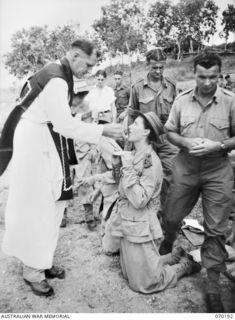 PORT MORESBY, NEW GUINEA. 1944-02-07. AN ARMY NURSE RECEIVES HOLY COMMUNION DURING REQUIEM MASS CONDUCTED BY WX17091 CHAPLAIN C.W. CUNNINGHAM, MBE., (ROMAN CATHOLIC) (1)