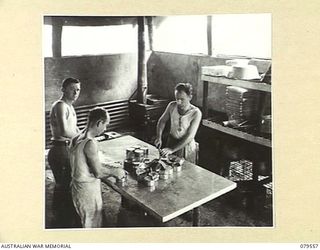 ORO BAY, NEW GUINEA. 1943-07. COOKS OPENING UP CANS OF TINNED MEAT DURING THE PREPARATION OF A MEAL IN THE KITCHEN OF THE 10TH FIELD AMBULANCE