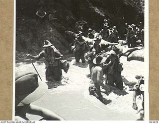 FARIA RIVER, RAMU VALLEY, NEW GUINEA. 1944-01-18. MEMBERS OF NO. 7 BATTERY, 2/4TH FIELD REGIMENT WADING THROUGH THE FAST FLOWING FARIA RIVER ON THEIR WAY TO FORWARD POSITIONS