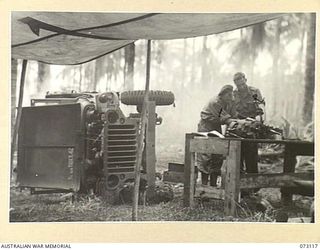 ALEXISHAFEN, NEW GUINEA. 1944-05-10. NX125627 CRAFTSMAN G.F. WHEAT (1), WITH NX142720 WARRANT OFFICER II, E. KETTERINGHAM (2), WORKING ON THE REPAIR OF A JEEP IN THE WORKSHOP OF THE 251ST LIGHT AID ..