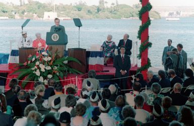 The crowd on the Kilo 8 Pier listens as President George Bush speaks during the observance of the 50th anniversary of the Japanese attack on Pearl Harbor. General Colin L. Powell, Chairman of the Joint Chiefs of STAFF, and first lady Barbara Bush is at left. (Substandard image)