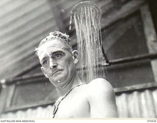 MADANG, NEW GUINEA. 1944-08-25. WX22038 LANCE CORPORAL K.C. STENHOUSE, 4TH INFANTRY BATTALION AND A PATIENT OF THE 2/11TH GENERAL HOSPITAL ENJOYING A SHOWER IN THE NEW WARD 2