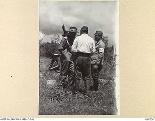 MALAGUNA MISSION, NEW BRITAIN. 1945-09-10. MAJOR W.J. MCPHERSON, BRIGADE MAJOR DISCUSSING MATTERS WITH TWO JAPANESE STAFF OFFICERS ON THE BEACH, DURING THE FIRST DAY OF THE OCCUPATION OF THE RABAUL ..