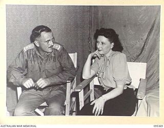 TOROKINA, BOUGAINVILLE, 1945-08-16. LIEUTENANT R.N. KEAM, 4 MILITARY HISTORY FIELD TEAM ATTACHED HEADQUARTERS 2 CORPS, TALKING WITH MISS PEGGY SHEA, A MEMBER OF THE GRACIE FIELDS CONCERT PARTY