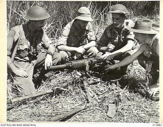 1942-12-17. PAPUA. FALL OF GONA. A CAPTURED JAPANESE MACHINE GUN. AT THE RIGHT IS FRED FOLKARD, SYDNEY "SUN" WAR CORRESPONDENT. (NEGATIVE BY BOTTOMLEY)