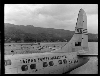 Aircraft Ararangi ZK-AMM, TEAL (Tasman Empire Airways Limited) at Papeete, Tahiti, and welcoming reception for passengers paddling back to mainland
