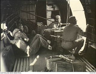 AIRBORNE OVER BOUGAINVILLE ISLAND. C. 1945-01-27. MEMBERS OF AN ARMY AIR MAINTENANCE COMPANY LAUNCHING SUPPLIES TO AUSTRALIAN MILITARY FORCES FORWARD TROOPS FROM INSIDE A DOUGLAS C47 DAKOTA ..