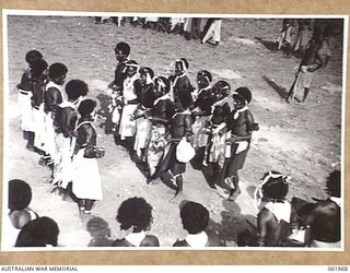 KILA KILA, PAPUA, NEW GUINEA. 1943-12-25. KEREMA BOYS EXECUTING A DANCE AT THE AUSTRALIAN AND NEW GUINEA ADMINISTRATION UNIT NATIVE LABOUR CAMP. THE DANCERS WEST LONG TRAILS OF GRASS AND FLOWERS, ..