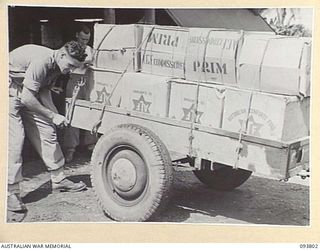 LAE AREA, NEW GUINEA, 1945-07-11. SIGNALMAN N.C. DELANEY, 1 COMPANY, 18 LINES OF COMMUNICATION SIGNALS, SECURING HAMPERS TO A TRAILER AT THE AUSTRALIAN COMFORTS FUND, LAE DISTRIBUTION CENTRE