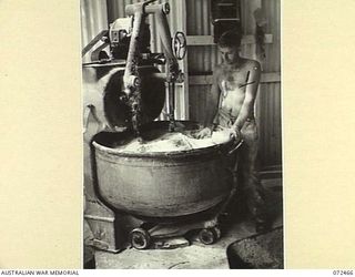 PORT MORESBY, NEW GUINEA. 1944-04-20. NX20097 PRIVATE C. SCHMIEDE, 6TH FIELD BAKING PLATOON, OPERATING A DOUGH MIXING MACHINE AT THE UNIT BAKERY