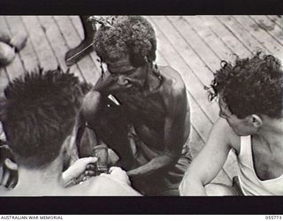 MOROBE, NEW GUINEA. 1943-08-13. WARRANT OFFICER 1 WILSON (LEFT) AND SKIPPER OF THE AS11, 1ST AUSTRALIAN WATER TRANSPORT GROUP (SMALL CRAFT), ROYAL AUSTRALIAN ENGINEERS, AND A MEMBER OF HIS CREW, ..