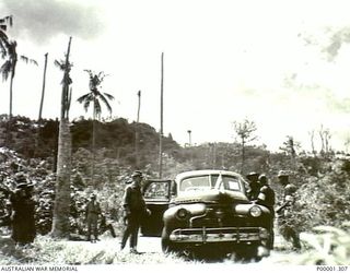 NEW BRITAIN, 1945-09. MEMBERS OF THE AUSTRALIAN MISSING PRISONERS INVESTIGATION UNIT (MPIU) WITH JAPANESE ASSISTANCE AND A MOTOR VEHICLE NEAR RABAUL. (RNZAF OFFICIAL PHOTOGRAPH.)