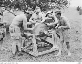 PAPUA. 1942-08-18. GETTING READY FOR THE JAPS. VETERANS OF THE SYRIAN CAMPAIGN, MEN OF THE 2/14TH AUSTRALIAN INFANTRY BATTALION SHARPEN THEIR BAYONETS ON A GRINDSTONE THEY HAD DISCOVERED IN A ..