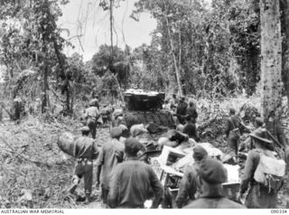 BOUGAINVILLE, 1945-04-05. A MATILDA TANK TOWING JEEP TRAILERS LOADED WITH AMMUNITION AND COVERED BY TROOPS OF 61ST INFANTRY BATTALION, MOVING ALONG BUIN ROAD. THE AREA BETWEEN BATTALION HQ AND B ..