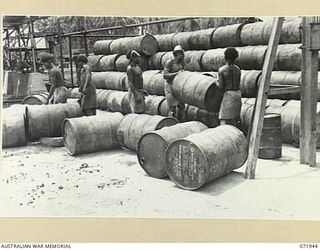 MILNE BAY, PAPUA, NEW GUINEA. 1944-04-03. NATIVES STACKING 44 GALLON DRUMS AT THE 2ND BULK PETROLEUM STORAGE COMPANY