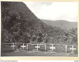 NANTAMBU, NEW BRITAIN, 1945-08-22. CORPORAL R. MORTON, 37/52 INFANTRY BATTALION STANDING BESIDE THE GRAVE OF A MEMBER OF HIS SECTION KILLED IN A JAPANESE CLASH AT COOPER'S CLEARING. THE GRAVES, ..