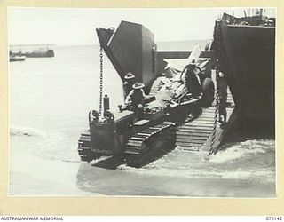 TSIMBA AREA, BOUGAINVILLE ISLAND. 1945-02-16. TROOPS OF NO. 12 FIELD BATTERY, 4TH FIELD REGIMENT, USING A SMALL TRACTOR TO LAND THEIR 25 POUNDER GUNS ON THE BEACH AT PUTO