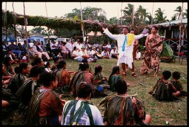 Man delivering a speech to dancers outdoors, Niue