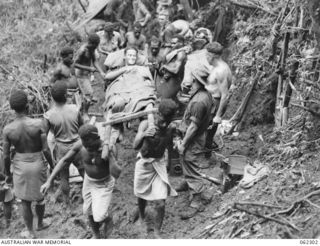 SHAGGY RIDGE, NEW GUINEA. 1943-12-27. NATIVE STRETCHER BEARERS SETTING OFF FOR THE 2/16TH AUSTRALIAN INFANTRY BATTALION, 21ST AUSTRALIAN INFANTRY BRIGADE REGIMENTAL AID POST ON A LONG WINDING TRACK ..