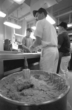 Navy and Marine mess management specialists aboard the amphibious assault ship USS SAIPAN (LHA-2) make cookies in preparation for the arrival of evacuees from the U.S. Embassy in Monrovia, Liberia. THE SAIPAN is on station off the coast of Liberia for OPERATION SHARP EDGE