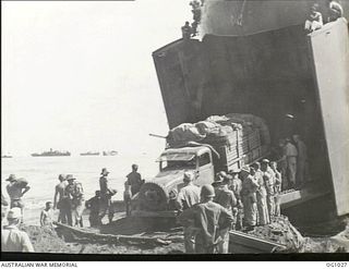 AITAPE, NORTH EAST NEW GUINEA. 1944-04-22. A TRUCK LADEN WITH STORES IS UNLOADED FROM THE LANDING SHIP, TANK (LST) ONTO A SPECIALLY BUILT RAMP ON THE BEACH BY MEMBERS OF RAAF MOBILE WORKS UNIT WHO ..