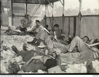 VIVIGANI, GOODENOUGH ISLAND, PAPUA. C. 1943-05. BEAUFIGHTER CREWS OF NO. 30 SQUADRON RAAF RELAX ON THE CORAL FLOOR OF A HUT. THEY ARE ON STANDBY AND READY TO TAKE OFF AT A MOMENT'S NOTICE. (SAME ..