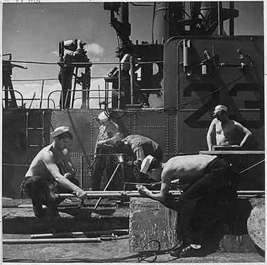 Enlisted men repair and check instruments aboard a submarine just returned to Pearl Harbor. Hawaii