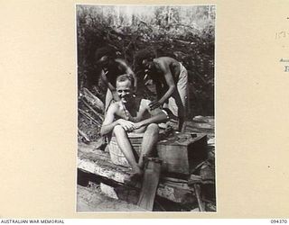 YAMIL 2, NEW GUINEA. 1945-07-20. PRIVATE D.R. HARTMANN-HUDSON, IN CHARGE OF LAUNDRY AT THE MAIN DRESSING STATION, 2/2 FIELD AMBULANCE (3) HAS HIS BACK SCRUBBED AT THE END OF A DAYS WORK BY MUNHOE ..