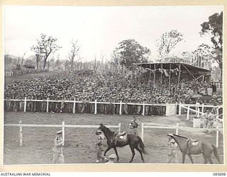 HERBERTON, QLD. 1945-01-20. UNIT STANDARDS FLYING FROM THE MAIN GRANDSTAND DURING THE 9 DIVISION GYMKHANA AND RACE MEETING AT HERBERTON RACECOURSE ORGANISED BY HQ 9 DIVISION. THE BETTING RING IS ..