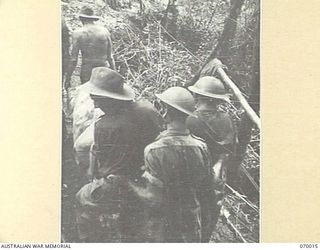 SHAGGY RIDGE, NEW GUINEA. 1944-01-10. STRETCHER BEARERS CARRYING AN UNKNOWN PRIVATE OF "A" COMPANY, 2/9TH INFANTRY BATTALION ON A NARROW TRACK CUT INTO THE SIDE OF SHAGGY RIDGE. A SHORT WAY FURTHER ..