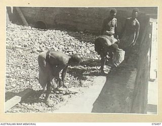 LAE, NEW GUINEA. 1944-10-18. NATIVES BUSILY ENGAGED IN MAKING A SWIMMING POOL AT THE LAE NATIVE LABOUR COMPOUND, AUSTRALIAN NEW GUINEA ADMINISTRATIVE UNIT, LAE BASE SUB AREA. THIS COMPOUND, HOUSING ..