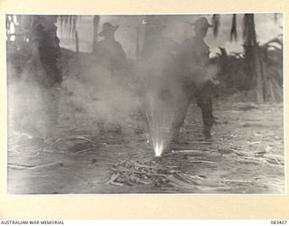 BABIANG AREA, NEW GUINEA, 1944-11-19. TROOPS OF 2/10 COMMANDO SQUADRON LIGHT A FLARE TO GIVE WIND DIRECTION AND SPEED APPROXIMATION TO A BEAUFORT BOMBER PILOT OF 100 SQUADRON, RAAF, FOR A SUPPLY ..